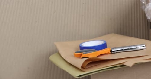 Different packaging materials and scissors, closeup. Camera moving right
