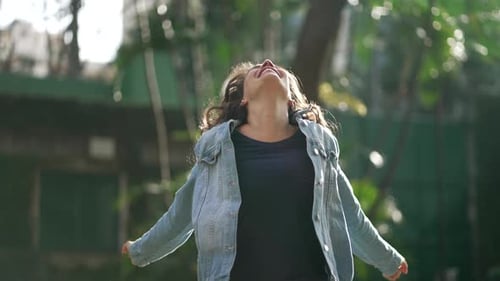 Joyful Young Woman Celebrating Success Outdoors During Golden Hour
