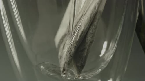 Extreme close up of a tea bag in a glass and hot water being poured in the glass