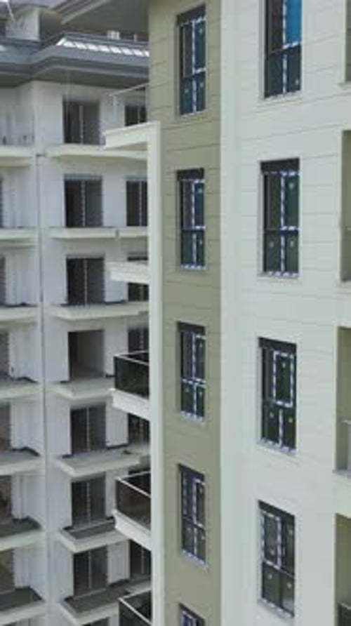 Vídeo vertical: máquinas pesadas colocan los cimientos en la parte inferior, mientras que los constructores añaden vidrio a los balcones y Fa Ade