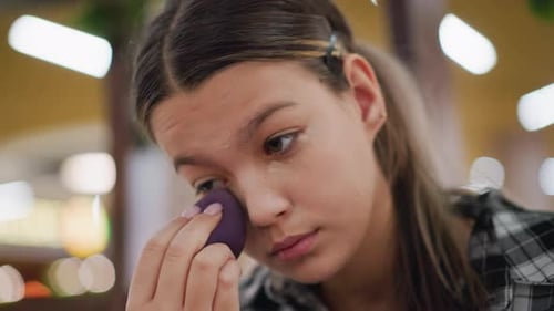 Closeup View of Girl Using Beauty Sponge to Blend Makeup Under Eyes