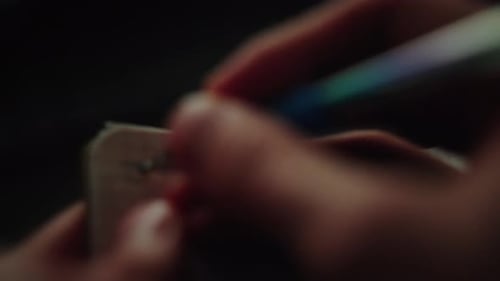 An individual is jotting down ideas with a pencil on a small notepad, contrasting against a black ba