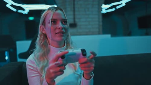 A Young Woman Plays a Console in a Room with Neon Lights