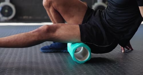 Foam roller, man and fitness in gym for muscle recovery, stretching and body tension or pain relief