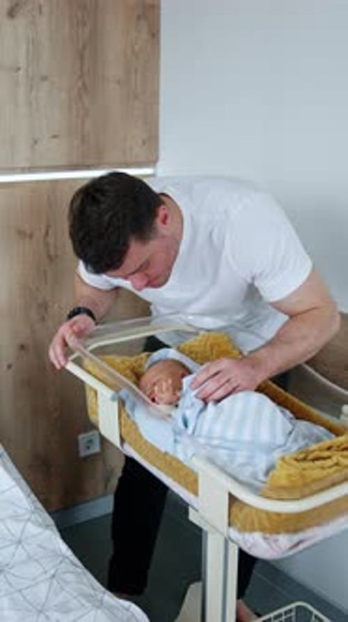 Loving Father Admires Newborn Baby in Crib