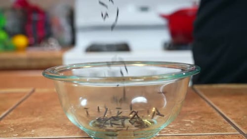 Pouring wild or black rice into a glass bowl in preparation for cooking - slow motion side view