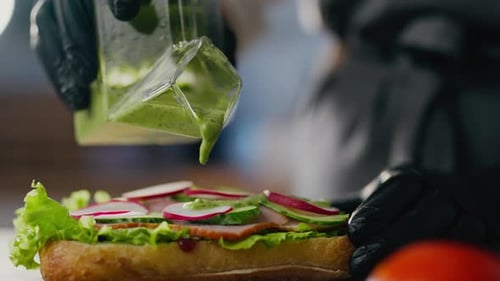 Street food, cook baker prepares professionally Add avocado sauce in a specialty sandwich eatery