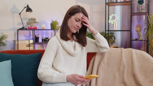 Worried Woman Using Smartphone on Couch