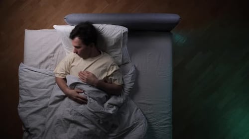 Man sleeping soundly in bed overhead shot