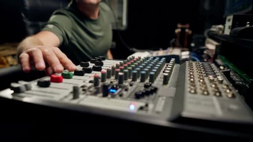 A close-up of a mixing console device used by a man working as professional sound engineer