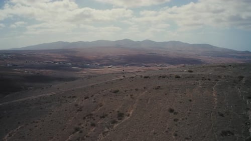 Drone shot of a girl walking on a mountain in fuerteventura
