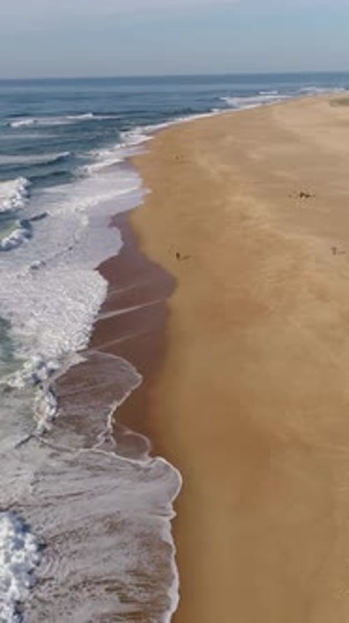 Waves of the Atlantic Ocean on Nazare Beach with a rocky cliff in the background in Nazare, Portugal