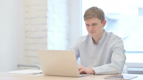 Young Adult Working on Laptop Gives Thumbs Up