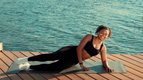 Woman Doing Leg Lifts on Dock By Calm Water