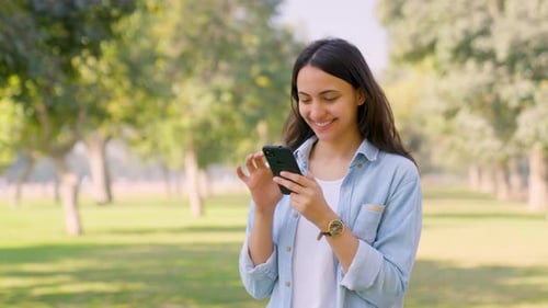 Smiling Woman Using Smartphone in Green Park
