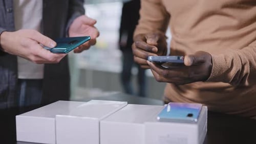 A Consultant in an Electronics Store Offers a Choice of New Smartphones to an African Man