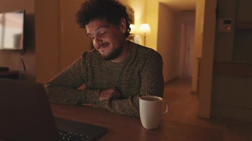 Smiling Man Talking on Laptop Video Call at Night