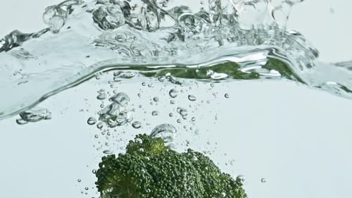 Broccoli Splashes into Water in Bright Studio Setting