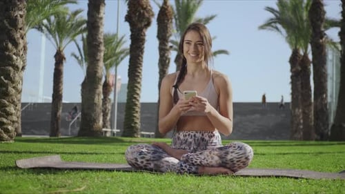 Athletic Woman Using Phone After Workout in Park
