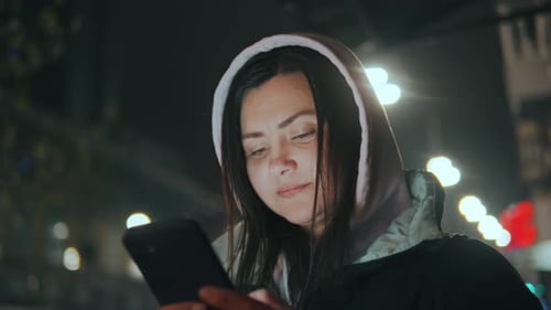 Woman Uses Smartphone at Night in City