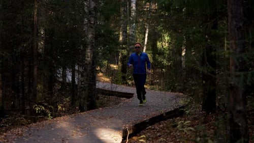 Man Running and Checking Smartwatch in Forest