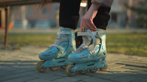 Person Fastening Rollerblade Straps in a Park Preparing for Activity