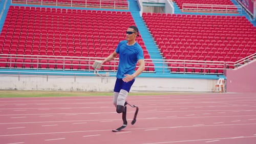 Asian para-athlete with prosthetic blades warms up body in the stadium.