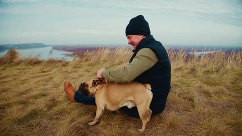 A Heartwarming Moment Between a Man and His Dog Outdoors Enjoying Each Other's Company in a Grassy