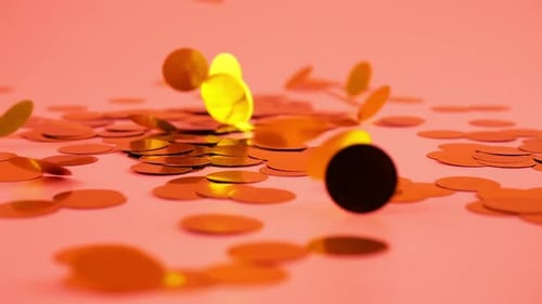 Falling confetti on a peach-pink background. Slow motion.