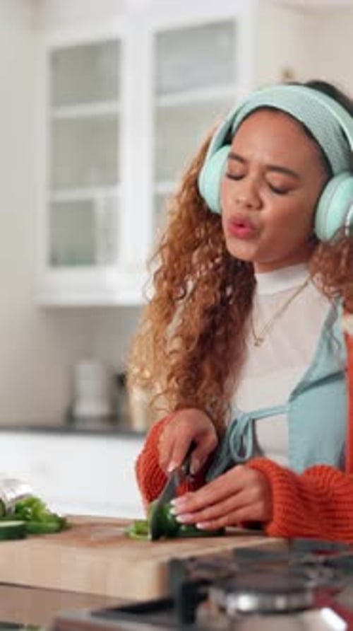 Smiling Woman Chopping Vegetables in Kitchen While Listening to Music