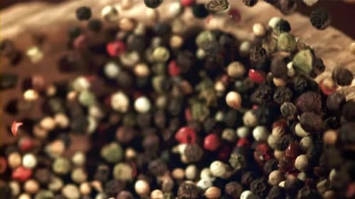 Colorful Peppercorns Falling into a Rustic Wooden Bowl