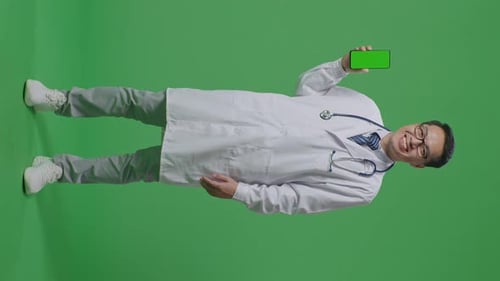 Full Body Of Asian Male Doctor Smiling And Showing Green Screen Smartphone On Green Screen