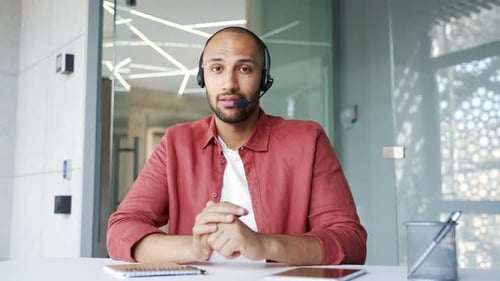 Webcam view. Confident businessman in headset talking on video call looking at camera sitting
