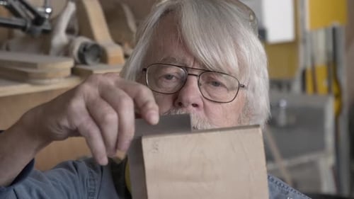 Senior Man Inspecting Wood Block with Measuring Tool