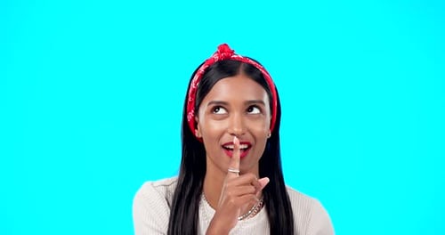Secret, face and happy woman with finger on lips in studio, blue background and privacy sign