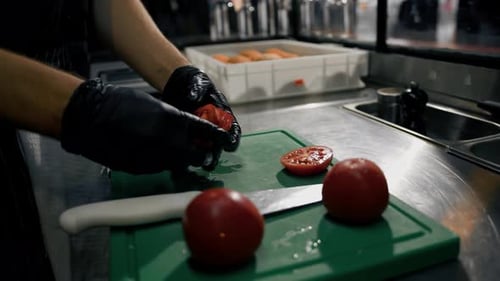 The chef cuts vegetables tomatoes on a cutting board in a restaurant in a professional kitchen