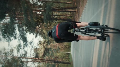 Cyclist sprinting on road bicycle, pushing pedals out of saddle. Vertical video