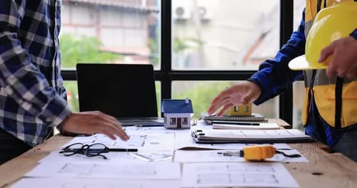Construction Workers Reviewing Blueprints and Shaking Hands