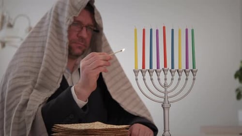 Una persona judía ortodoxa enciende una menorá de Hanukkah con velas de colores