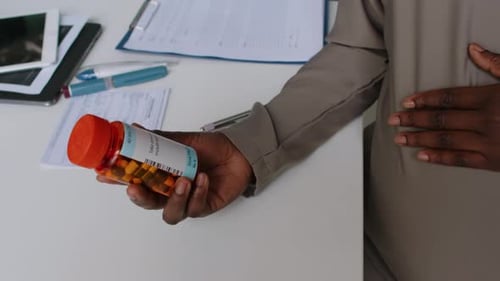 Unrecognizable Pregnant Woman Holding Jar of Prescription Pills in Clinic