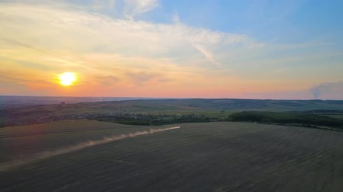 Tractor Spraying Fertilizers with Insecticide Herbicide Chemicals on Agricultural Field at Sunset