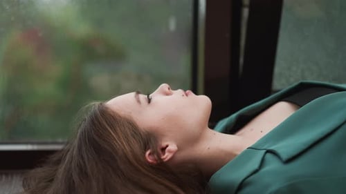 Woman Lying Down in Front of Rainy Window