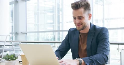 4k video footage of a handsome young businessman working on his laptop in the office
