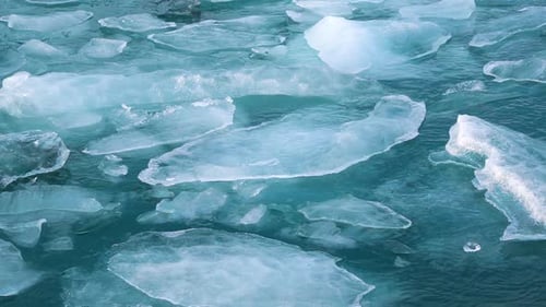 Small blocks and thin slices of ice floating on Jokulsarlon glacier lake surface, slowly melting in