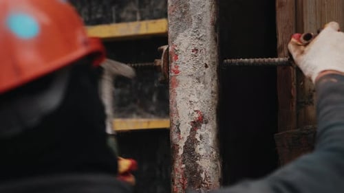 Worker Tightening Formwork Wing Nut with Hammer During Wall Assembly