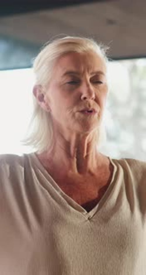 Senior Woman Meditates Indoors with Hands in Prayer Position