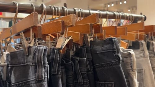 Close up rack of jeans clipped on hangers on display in store, clearance sale