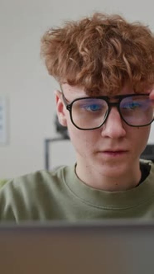 Teenage Boy Wearing Glasses Working On Laptop In School
