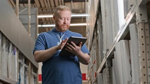 Warehouse Worker Using Tablet for Inventory in Aisle