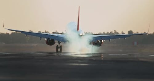 A Passenger Plane Lands on the Runway at Sunset